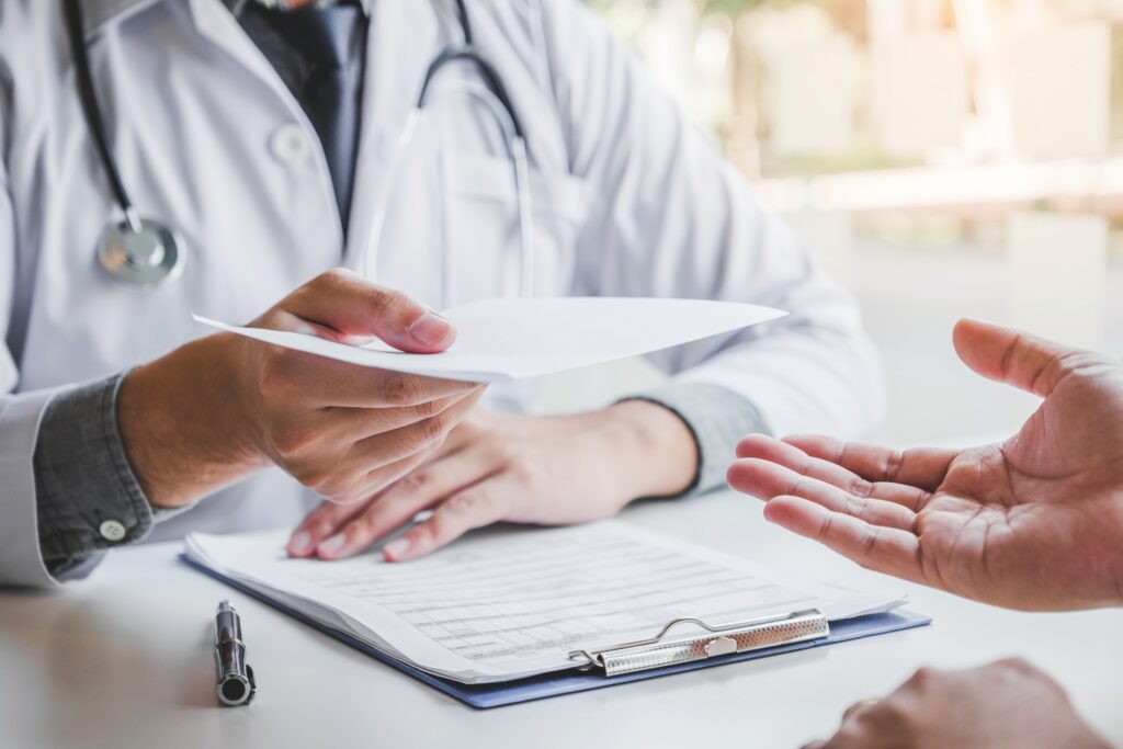 Medico consegna la documentazione a un paziente durante una visita specialistica
